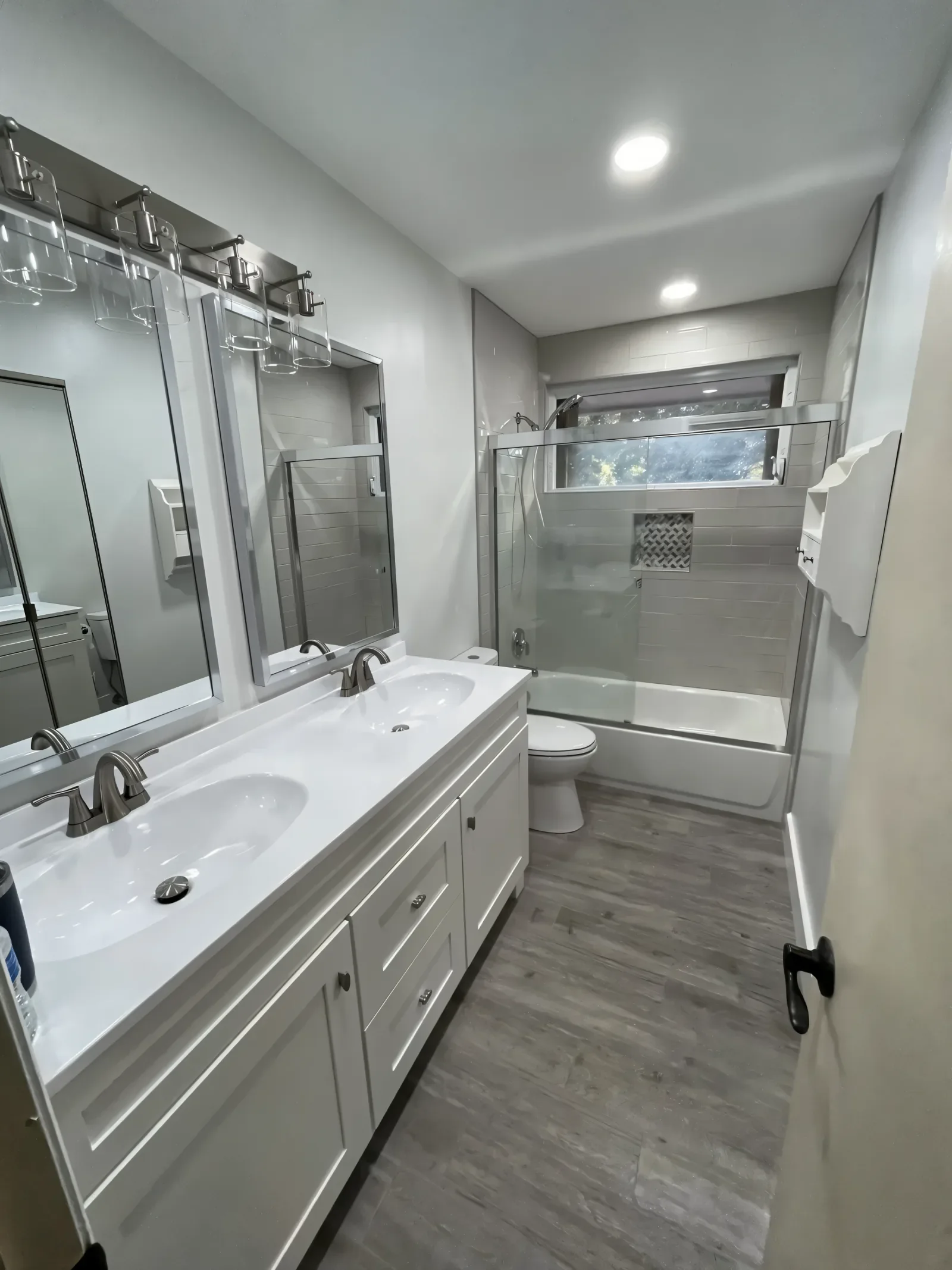 Finished bathroom with a white double vanity and a glass shower