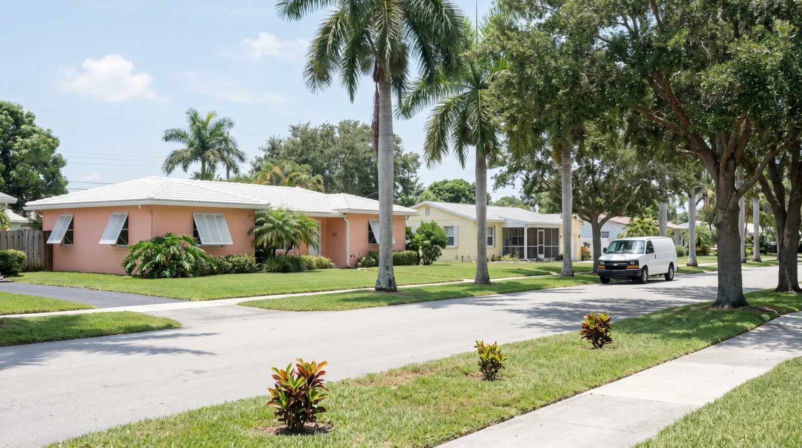 A quiet residential street in West Palm Beach, Florida, lined with palm trees, single-family homes, and a parked white work van.