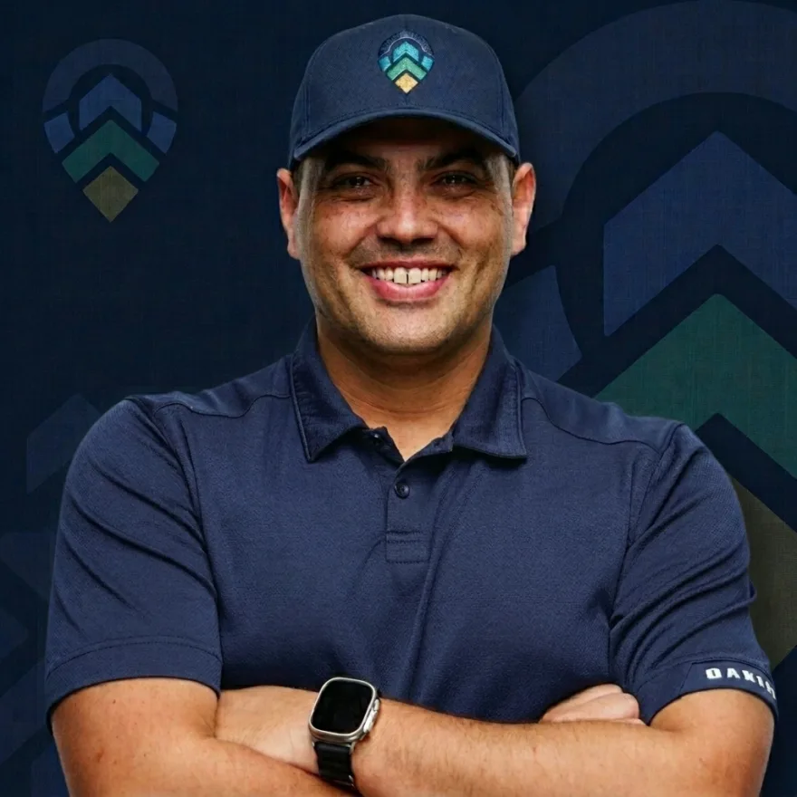 Jerry Camacho, founder of FoundRank.AI, smiling with arms crossed in a FoundRank cap in front of the brand's rising chevron logo.