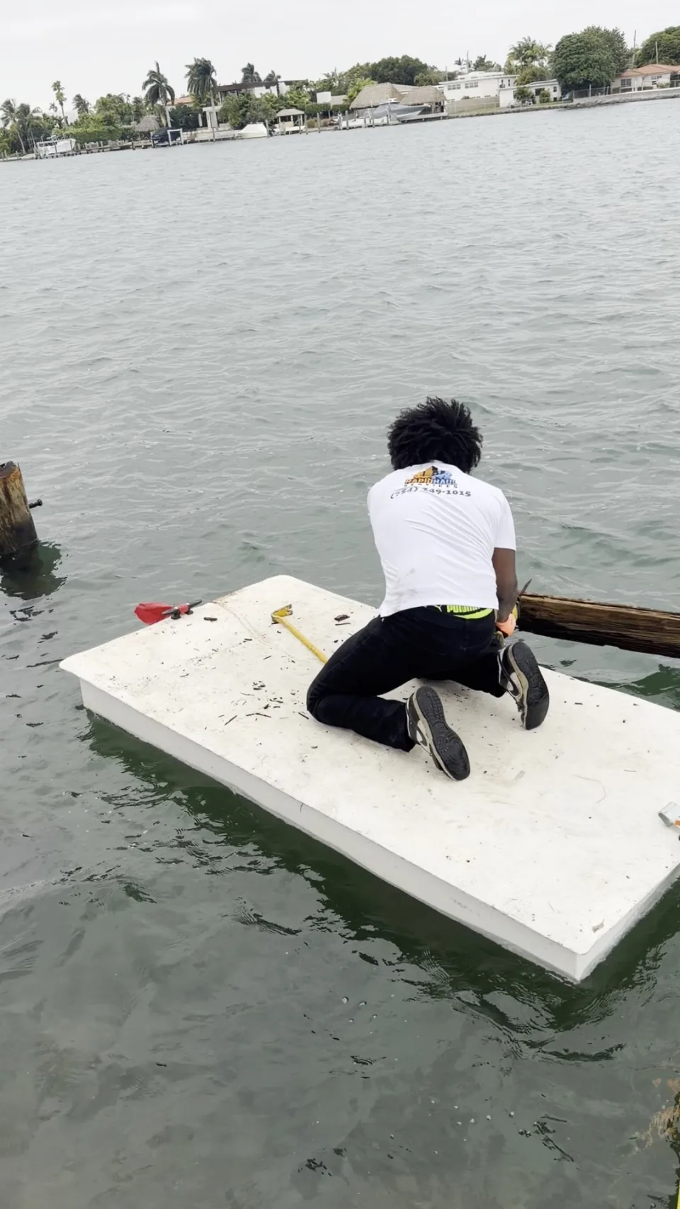 Rapid Haul crew member on a floating platform pulling an old dock piling in Coral Gables